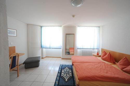 a bedroom with two beds and a desk and two windows at Chez Gilles hôtel resto bar SA in La Chaux-de-Fonds