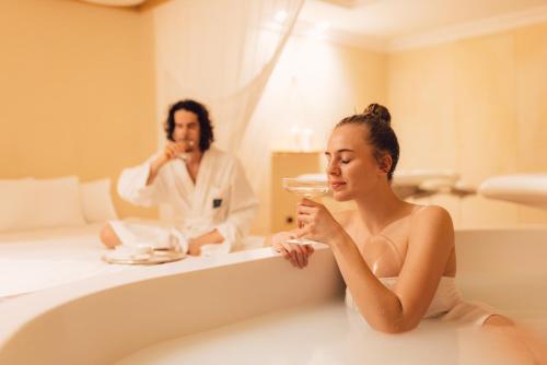 Eine Frau, die mit einem Mann in einer Badewanne sitzt. in der Unterkunft Alpenpalace Luxury Hideaway & Spa Retreat in Luttach