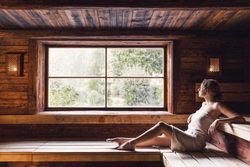 a woman sitting on a window sill in a cabin at Alpenpalace Luxury Hideaway & Spa Retreat in Lutago
