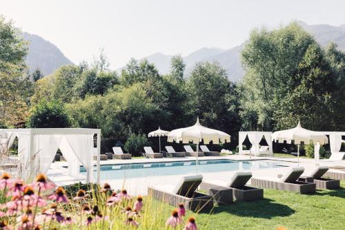a swimming pool with lounge chairs and umbrellas at Alpenpalace Luxury Hideaway & Spa Retreat in Lutago