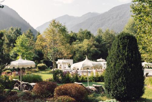 a group of tents in a garden with mountains in the background at Alpenpalace Luxury Hideaway & Spa Retreat in Lutago