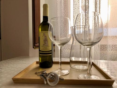 a wooden tray with two wine glasses and a bottle of wine at Ankon Apartments Palazzo Mazzini in Ancona