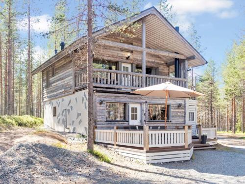 a wooden house with an umbrella in front of it at Holiday Home Uuttuniemi by Interhome in Kuusamo