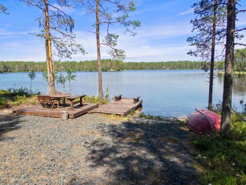 a picnic table and bench on the shore of a lake at Holiday Home Uuttuniemi by Interhome in Kuusamo