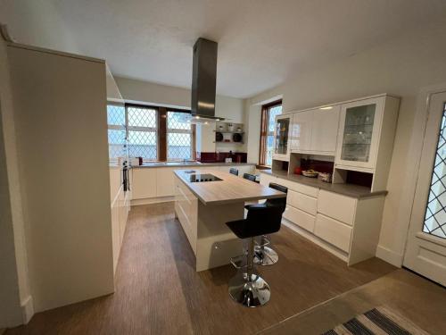 a large kitchen with white cabinets and a bar stool at Ashley House in Inverness