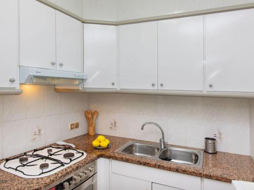 una cocina con armarios blancos y fregadero en Apartment Portbou by Interhome, en Portbou