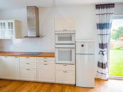 a kitchen with white cabinets and a refrigerator at Holiday Home Pusteblume by Interhome in Hessenburg