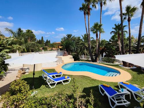 ein Pool mit Stühlen und Sonnenschirmen in einem Hof in der Unterkunft Holiday Home Villa Jolanda by Interhome in Denia