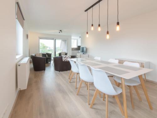 a dining room and living room with a white table and chairs at Apartment Rozenhof by Interhome in Bredene
