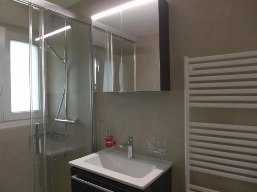 a bathroom with a sink and a shower with a mirror at Apartment Victoria A-B-C-10 by Interhome in Crans-Montana