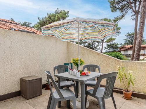 une table et des chaises avec un parasol sur une terrasse dans l'établissement Apartment Parc d'hiver by Interhome, à Mimizan