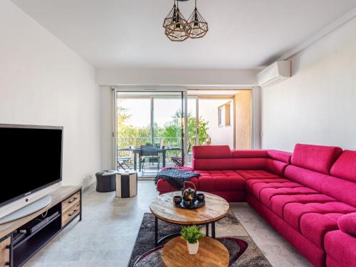 a living room with a red couch and a tv at Apartment Le Phenicia by Interhome in Saint-Laurent-du-Var