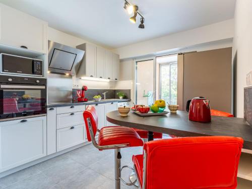 une cuisine avec une table en bois et des chaises rouges dans l'établissement Apartment Le Phenicia by Interhome, à Saint-Laurent-du-Var
