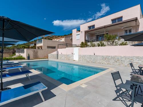 een zwembad met stoelen en parasols naast een gebouw bij Villa Villa Santa Reparata by Interhome in Porto-Vecchio