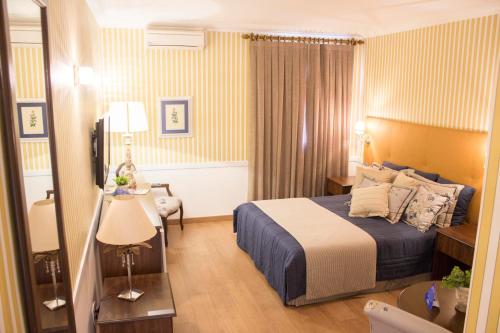 a hotel room with a bed and a table at Hotel Dan Inn Araraquara in Araraquara