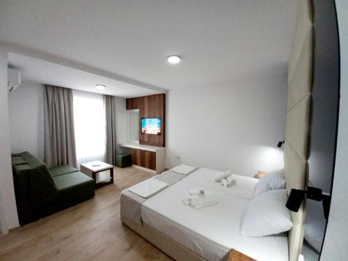 a bedroom with a white bed and a green couch at RIBAR APARTMENTS in Ohrid