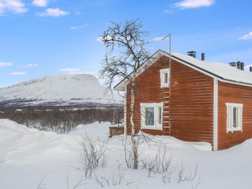 una cabaña de madera en la nieve con una montaña en el fondo en Holiday Home Saana 1 by Interhome en Kilpisjärvi