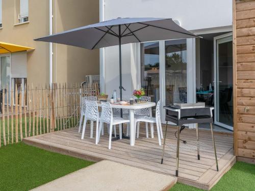 une table et des chaises avec un parasol sur une terrasse dans l'établissement Apartment Soleil Couchant B03 by Interhome, à Mimizan