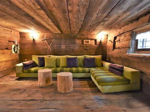 a living room with a green couch and two tables at Chalet Baita Barin by Interhome in Madesimo