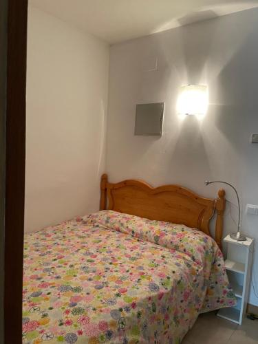 a bedroom with a bed with a floral bedspread and a light at Sol i Neu in Encamp