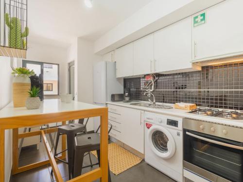 a kitchen with white cabinets and a washer and dryer at Apartment Wave Dream by Interhome in Olhão