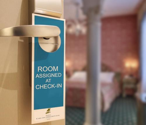 a sign on a door of a room with a bed at Hotel Carlton On The Grand Canal in Venice