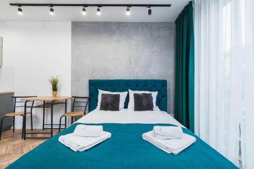 a bedroom with a blue bed with towels on it at Ice Apartments in Kraków