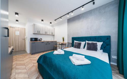sypialnia z niebieskim łóżkiem i ręcznikami w obiekcie Ice Apartments w Krakowie