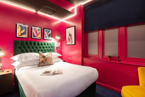 a bedroom with a large bed with pink walls at Hux Hotel, Kensington in London