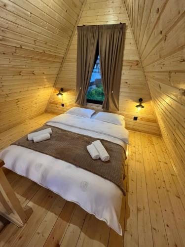 a large bed in a wooden room with a window at Cottage Carpe Diem in Stepantsminda