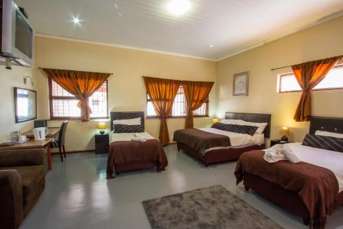 um quarto com 3 camas, um sofá e uma televisão em Ramasibi Guest Services em Panorama