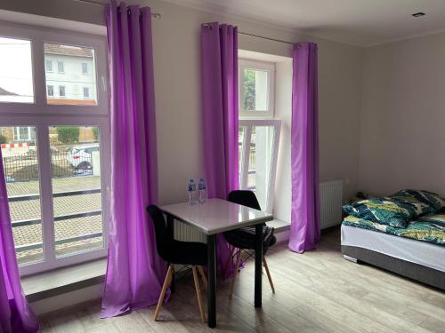 a bedroom with purple curtains and a table and a bed at Apartamenty Bezrzecze in Szczecin