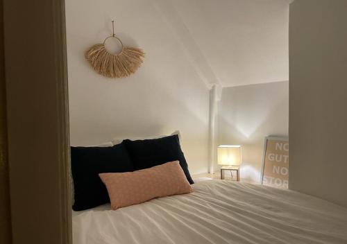 um quarto com uma cama branca e uma almofada rosa em Characteristic ground floor apartment with box bed em Groningen