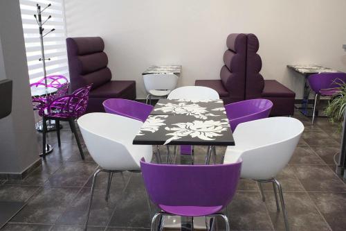 a table with purple and white chairs in a room at Incanto Family Hotel in Sevlievo