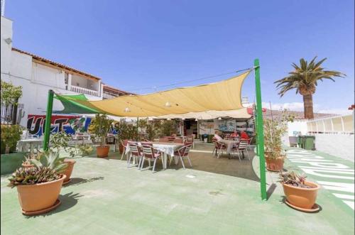 eine Terrasse mit einem Zelt, Tischen und Stühlen in der Unterkunft Casa lele en anfi del mar in Los Caideros