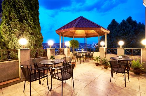 un patio con mesas y sillas y un cenador en Iliani Hotel, en Tiflis