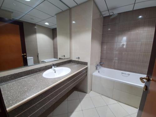 a bathroom with a sink and a tub and a mirror at Beachfront Holiday Homes in Ajman 