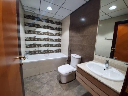 a bathroom with a toilet and a tub and a sink at Beachfront Holiday Homes in Ajman 
