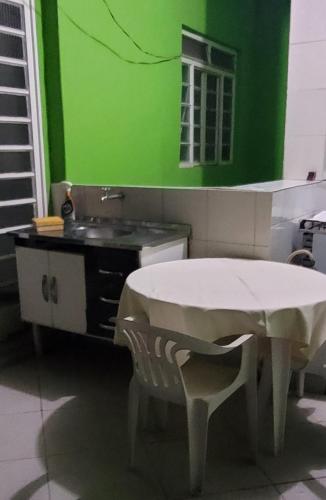 a green kitchen with a table and a sink at Aconchego Sagrada Face in Aparecida