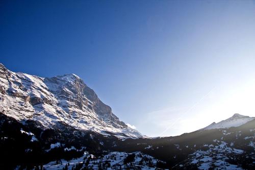 een met sneeuw bedekte berg met een vlieger in de lucht bij Studio Eigerblick in Grindelwald