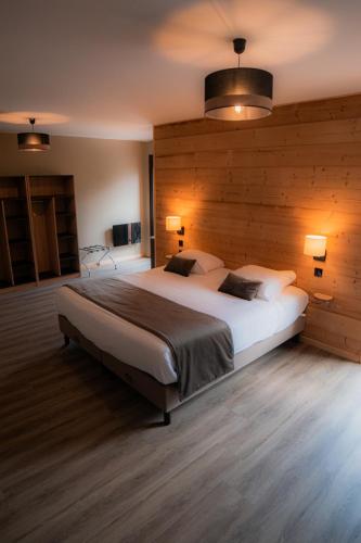 a bedroom with a large bed with wooden walls at Hôtel Le Picors in Aucun