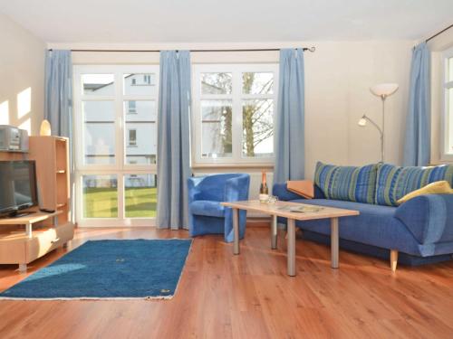 un soggiorno con divano blu e tavolo di Villa Seerose - Appartement 01 a Ostseebad Sellin