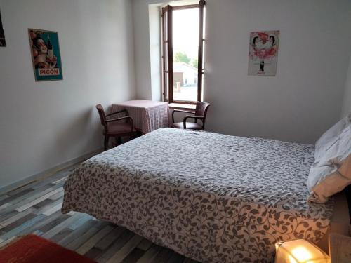 a bedroom with a bed and a table and a window at La Petite Auberge in Lorquin