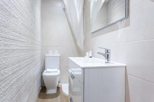 biała łazienka z umywalką i toaletą w obiekcie ApartEasy - Goya Ground Floor Studio w Madrycie