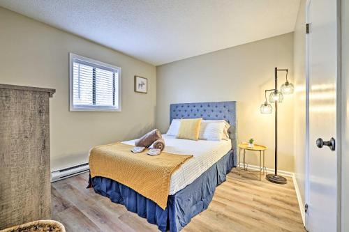 Schlafzimmer mit einem Bett mit blauem Kopfteil und einem Fenster in der Unterkunft Golf, Ski and Fish Cabin with Deck in Tobyhanna! in Tobyhanna