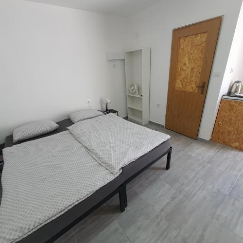 1 dormitorio con 1 cama y puerta de madera en Budget Apartment LeLo Center 4 en Osijek