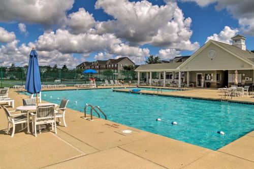 a swimming pool with chairs and a blue umbrella at Porch and Community Perks Walkable Lewes Condo in Lewes