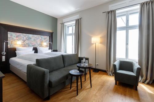 a bedroom with a bed and a couch and a chair at Hotel Alte Post in Konstanz