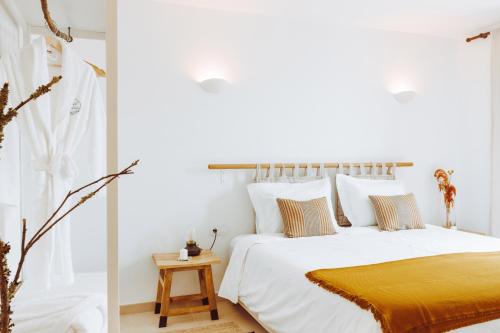 - une chambre avec un lit blanc et une couverture jaune dans l'établissement Oliveiras Village — Agroturismo, à Amarante