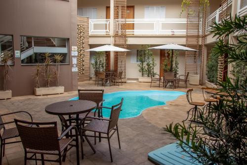 a patio with tables and chairs and a swimming pool at Casagrande Olímpia Hotel in Olímpia